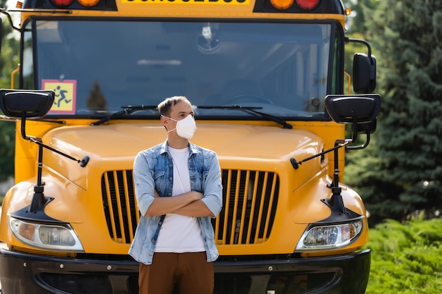 profesor enmascarado cerca del autobús escolar
