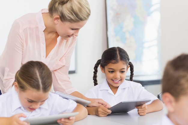 Profesor enseñando a colegiala en tableta digital