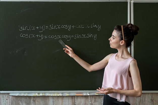 Profesor escrito en las fórmulas matemáticas de la junta escolar Álgebra