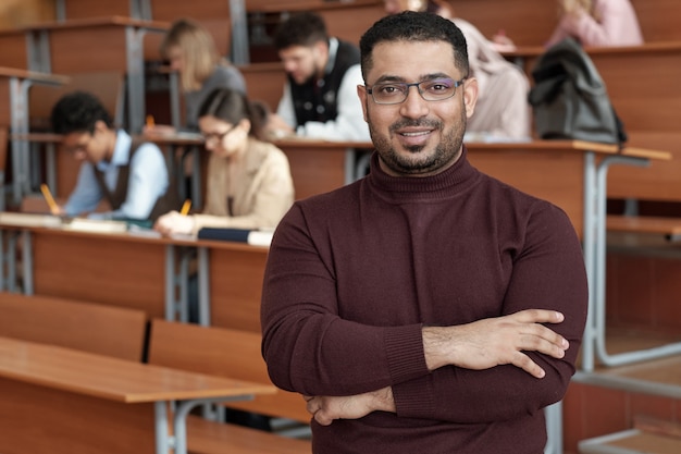 Foto profesor exitoso de la universidad de pie contra un grupo de estudiantes