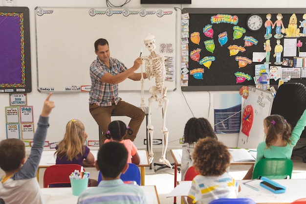 Foto profesor explicando sobre el esqueleto humano en el aula en la escuela