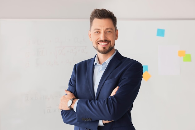 Profesor feliz en la pizarra en el aula durante la lección de matemáticas