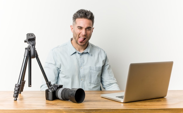 Profesor de fotografía guapo joven divertido y amable sacando la lengua