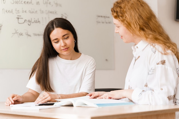 Profesor de inglés pregunta estudiante en clase blanca