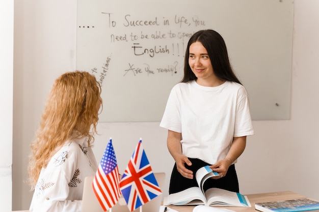 Foto profesor de inglés pregunta estudiante en clase blanca