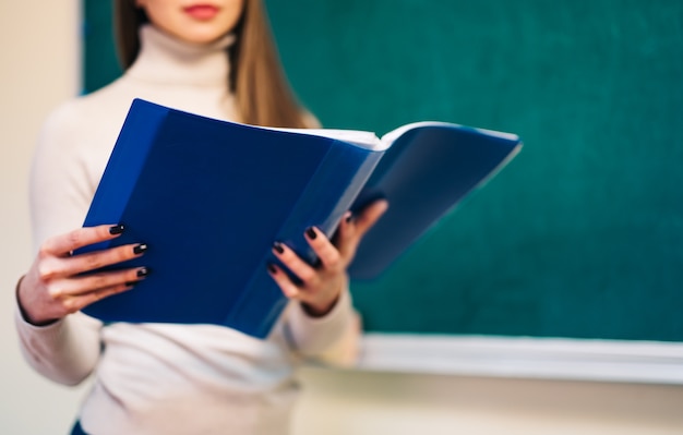 Profesor joven con una carpeta en el aula.