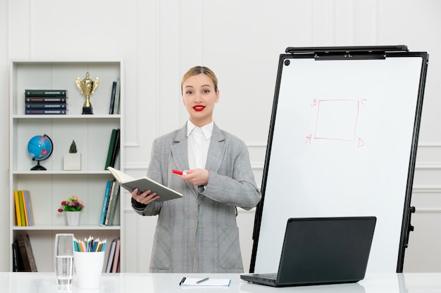 Profesor lindo instructor en traje en clase con computadora y pizarra con bloc de notas