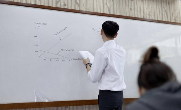 El profesor de matemáticas o física está trabajando en enseñar a los estudiantes de secundaria en el aula.