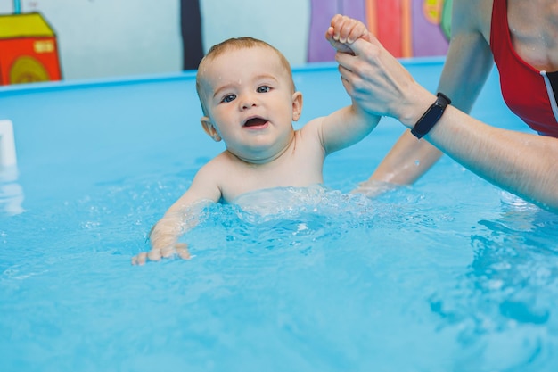 Un profesor de natación le enseña a un niño pequeño a nadar en la piscina Primeras lecciones de natación para niños Desarrollo para bebés