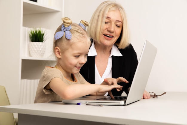 Profesor con niña escribiendo en la computadora portátil en el aula