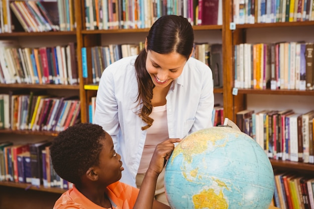 Profesor y niño mirando el mundo en la biblioteca