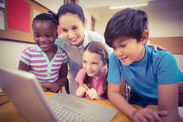 Foto profesor que usa la computadora portátil con los alumnos