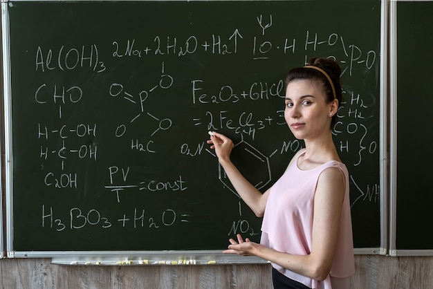 Foto profesor de química contra la fórmula química de explane de pizarra, concepto de educación