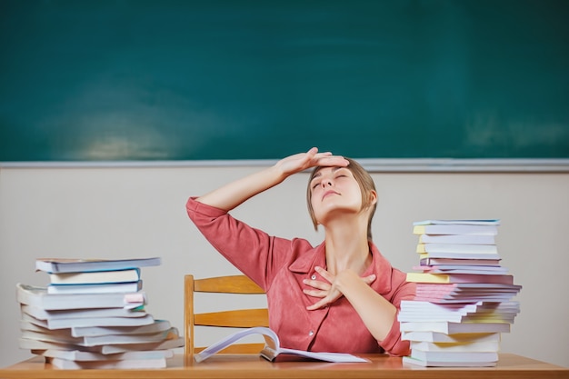 Profesor rodeado de libros en un aula de la escuela