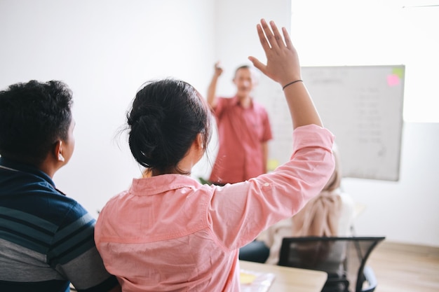 Profesor señalando a un estudiante universitario con la mano levantada en el aula