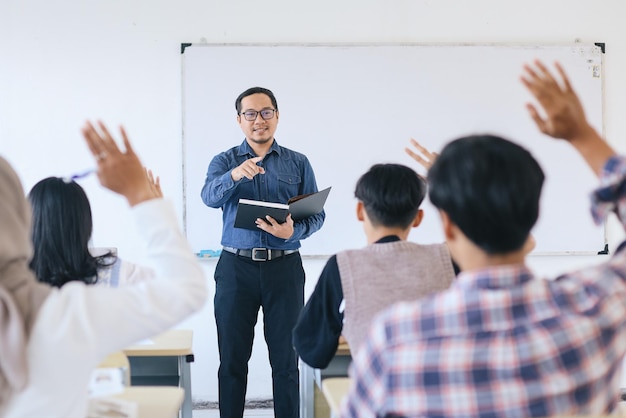 Profesor señalando a un estudiante universitario con la mano levantada en el aula