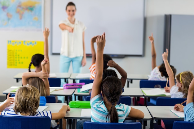 Profesor señalando a los estudiantes con las manos levantadas