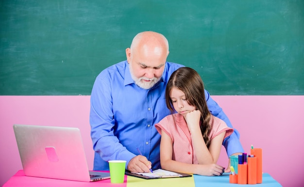 Profesor senior y niña en la lección de la escuela Método de enseñanza moderno Conocimiento moderno Educación moderna Estudiante feliz Estudiante niña con maestro hombre en pizarra Colegiala y tutor con computadora portátil