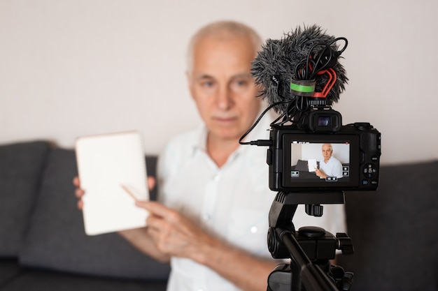 Profesor senior de oído gris haciendo un video para una conferencia en casa