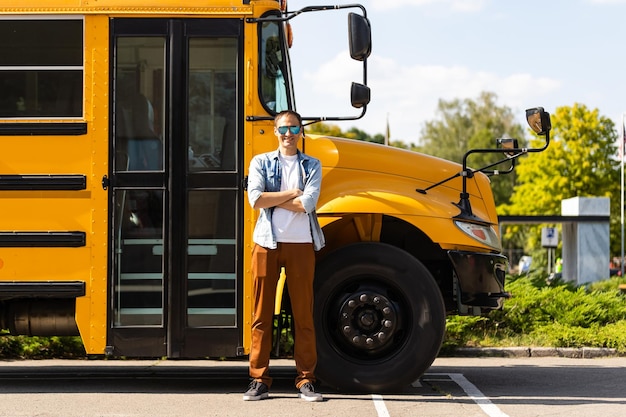 Un profesor de sexo masculino feliz cerca del autobús escolar