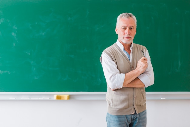 Profesor de sexo masculino mayor que se opone a la pizarra verde