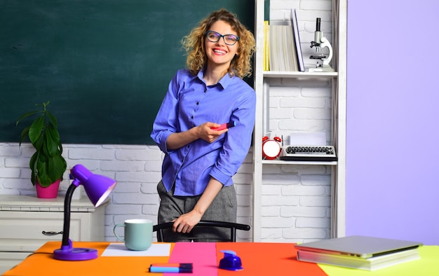 Foto profesor sonriente en el aula joven profesora joven profesora en vasos sobre pizarra verde