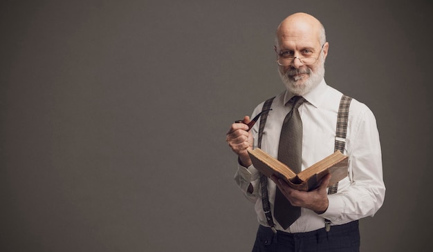 Profesor sonriente fumando una pipa y leyendo