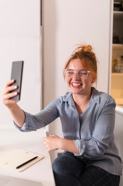 Profesor sonriente con smartphone para realizar una clase en línea