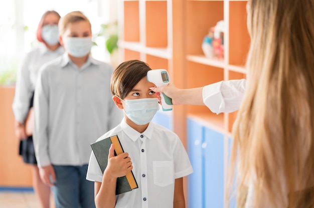 Foto profesor tomando la temperatura corporal en la escuela