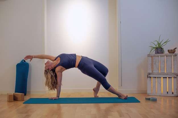 Profesor de yoga realizando posición de yoga en el interior de la alfombra en la escuela