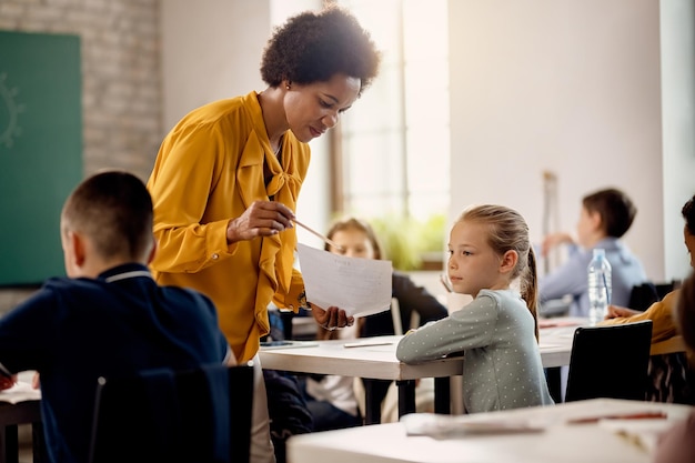 Profesora afroamericana y colegiala analizando los resultados de las pruebas durante una clase