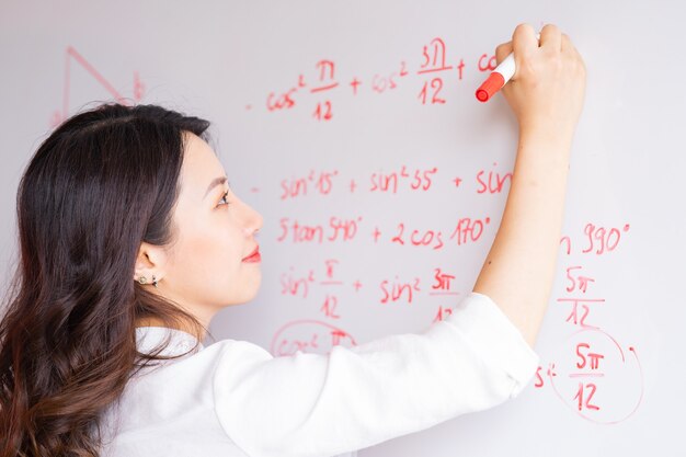 La profesora asiática está reescribiendo la conferencia en la pizarra