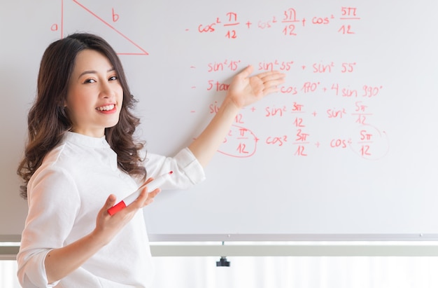 La profesora asiática está reescribiendo la conferencia en la pizarra