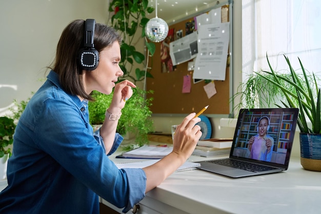 Profesora en auriculares enseñando a una joven estudiante en línea