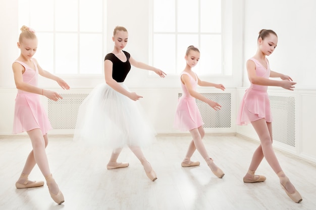 Foto profesora de ballet joven y estudiantes bailarinas en clase de baile. las niñas participan en la coreografía en la escuela de ballet, espacio de copia
