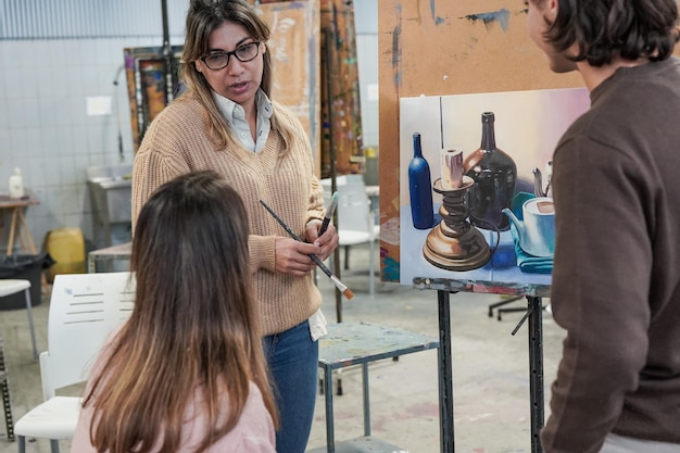 Profesora latina trabajando con estudiantes dentro de la sala de clase de arte en la universidad