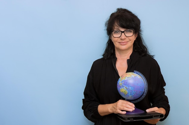 Profesora sonriente con tableta y globo sobre fondo azul con espacio de copia