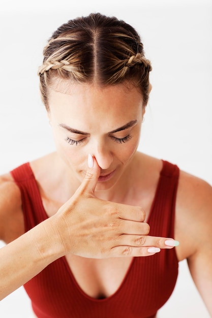 Una profesora de yoga está presionando su fosa nasal derecha para hacer respiraciones alternas