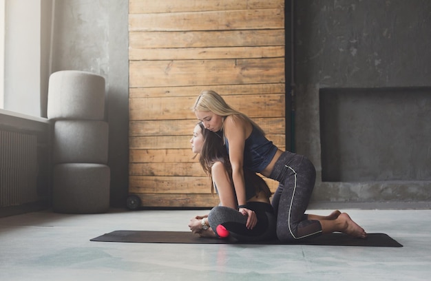 Profesora de Yoga y principiante en clase, realizando ejercicios de asanas. Pose de loto. Estilo de vida saludable en el gimnasio. Estirar con el entrenador