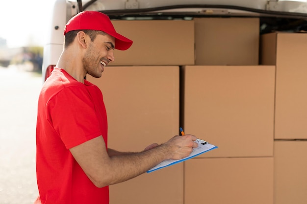 Foto professional young delivery man in uniform checking delivery list before handed to his customer