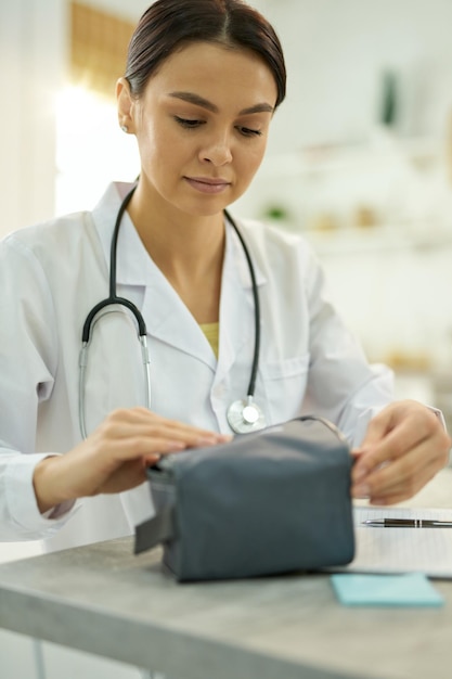 Professionelle Ärztin packt ihre medizinische Ausrüstung in eine Tasche