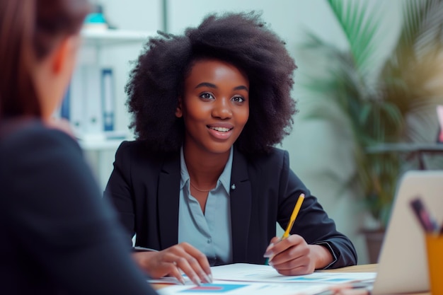 Professionelle afroamerikanische Frau unterhält sich mit einem Kollegen, der im Büro sitzt