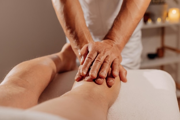 Professionelle Beinmassage im Spa-Salon auf dem Hintergrund von Kerzen