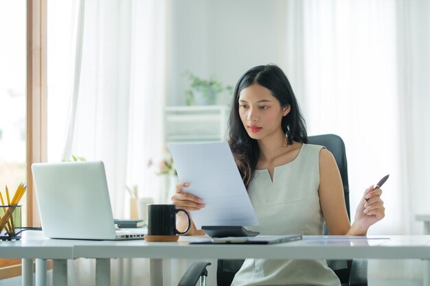 Professionelle Buchhalterin, die mit Finanzstatistikdiagrammen am Bürotisch x9 arbeitet