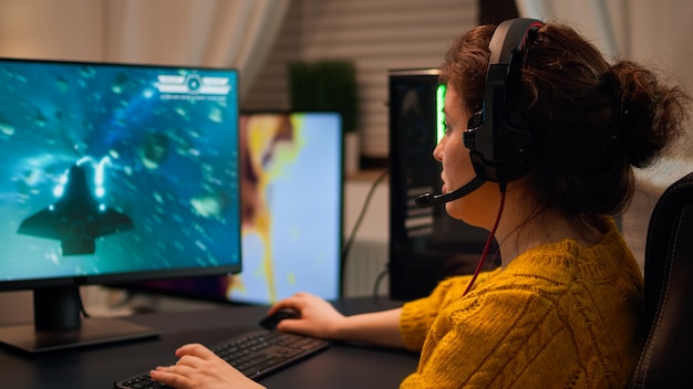 Professionelle E-Sport-Spielerin mit Mikrofon des Headsets, die ein Shooter-Spiel mit dem Team auf Streaming-Diensten spielt. Virtuelles Shooter-Spiel im Cyberspace, eSports-Spieler bei einem PC-Gaming-Turnier