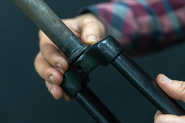 Professionelle Fahrradreparatur in der Werkstatt Der Mechaniker repariert die alte starre Gabel des Fahrrads Austausch des Lenksäulenlagers Details einer Fahrradgabel auf schwarzem Hintergrund