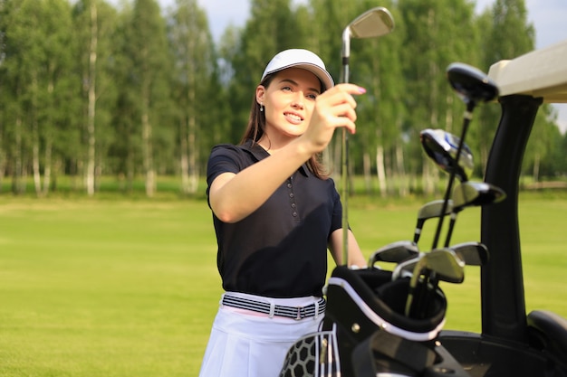 Professionelle Golfspielerin, die den Golfclub aus der Tasche wählt.