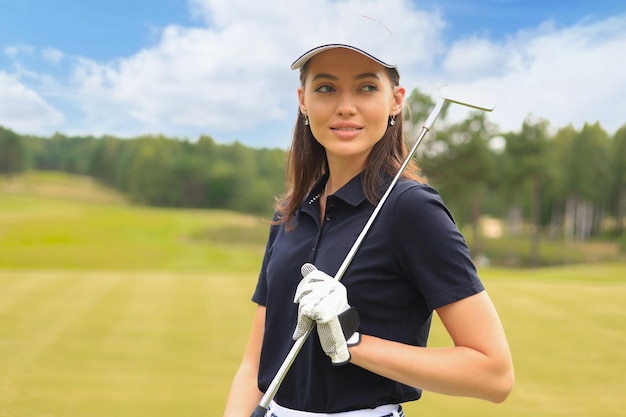 Professionelle Golfspielerin, die Golfschläger auf dem Feld hält und wegschaut. Junge Frau, die an einem sonnigen Tag auf dem Golfplatz steht.