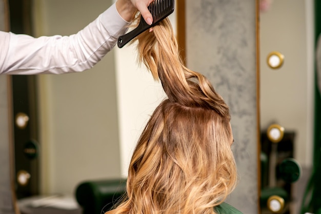 Professionelle Haarpflege Junge blonde Frau mit langen Haaren, die in einem Schönheitssalon Haarstyling erhält
