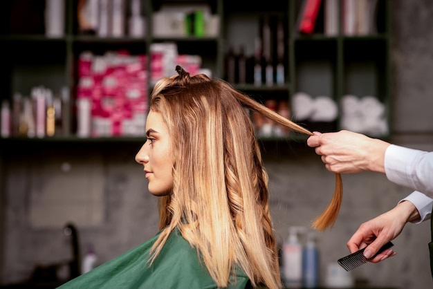 Professionelle Haarpflege Schöne junge kaukasische blonde Frau mit langen Haaren, die in einem Schönheitssalon ein Haarstyling erhält